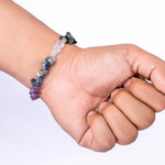 Hand wearing a beaded bracelet on a white background