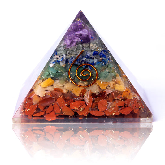 Triangular crystal orgone pyramid with colorful stones and a central spiral design on a white background.