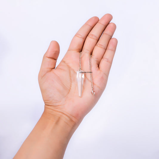 Hand holding a delicate necklace with a clear pendant against a light background