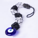 Necklace with blue evil eye pendant and black and white beads on a white background