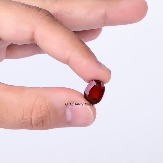 Hand holding a red gemstone with 'CHACHAN STONES' branding on a white background