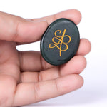 Black object with gold symbol held in a hand against a white background