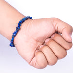 Hand wearing a blue beaded bracelet on a white background