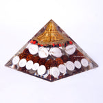 Pyramid-shaped crystal orgone with various stones on a white background