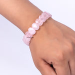 Pink beaded bracelet on a wrist against a white background