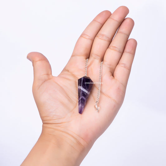 Hand holding a purple crystal pendulum with a white background