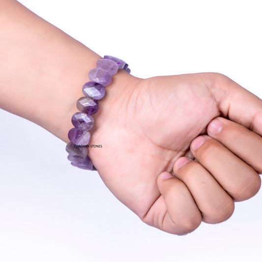 Hand wearing a purple beaded bracelet on a white background