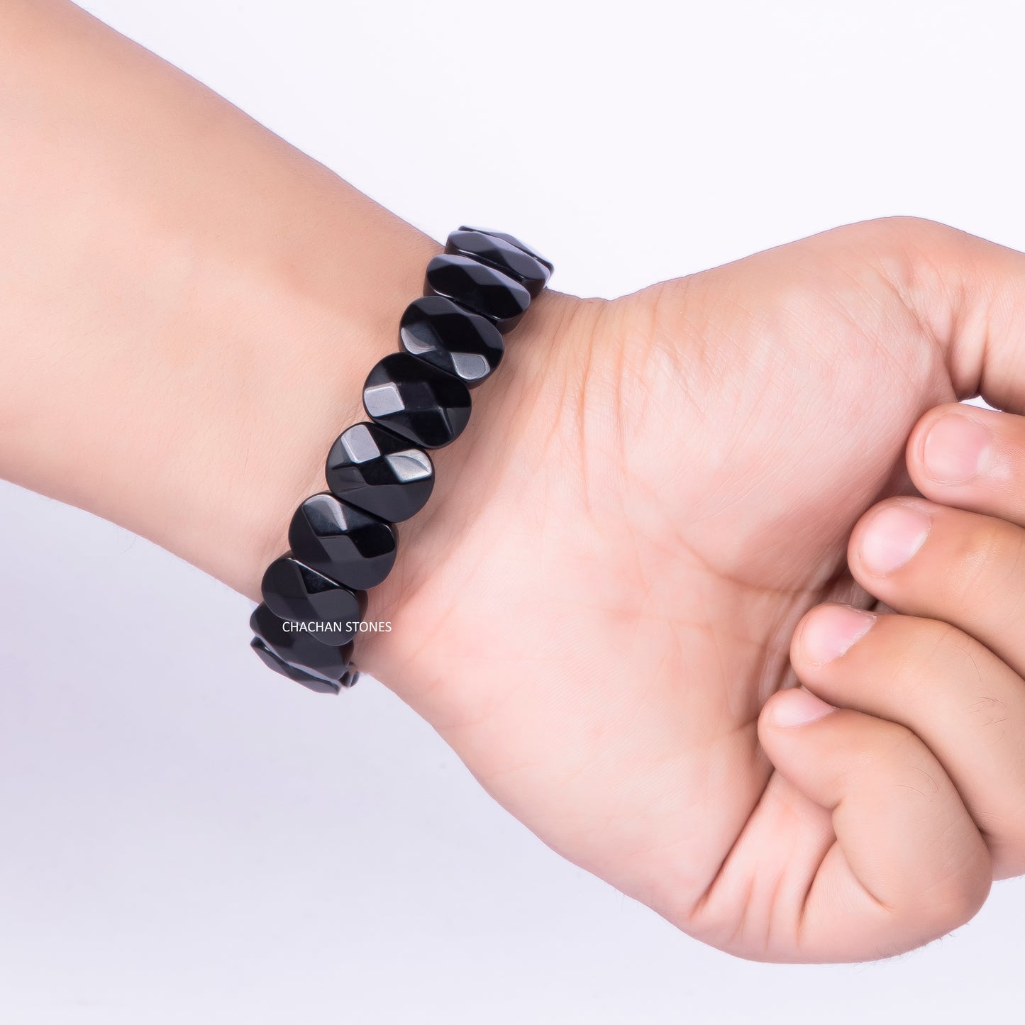 Black beaded bracelet on a wrist with a plain background