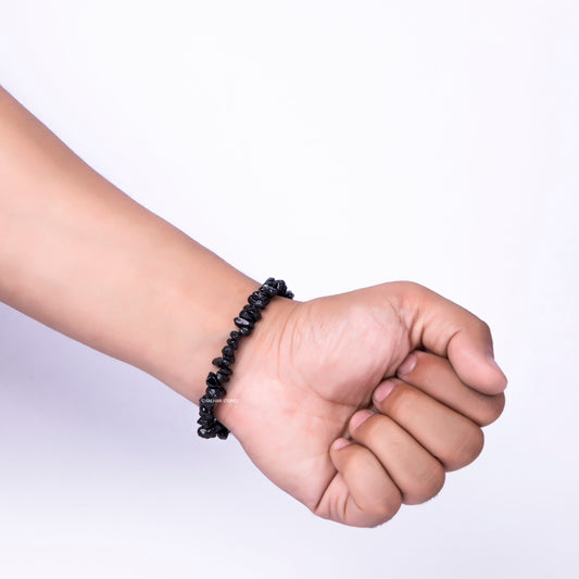 Hand wearing a black beaded bracelet on a white background