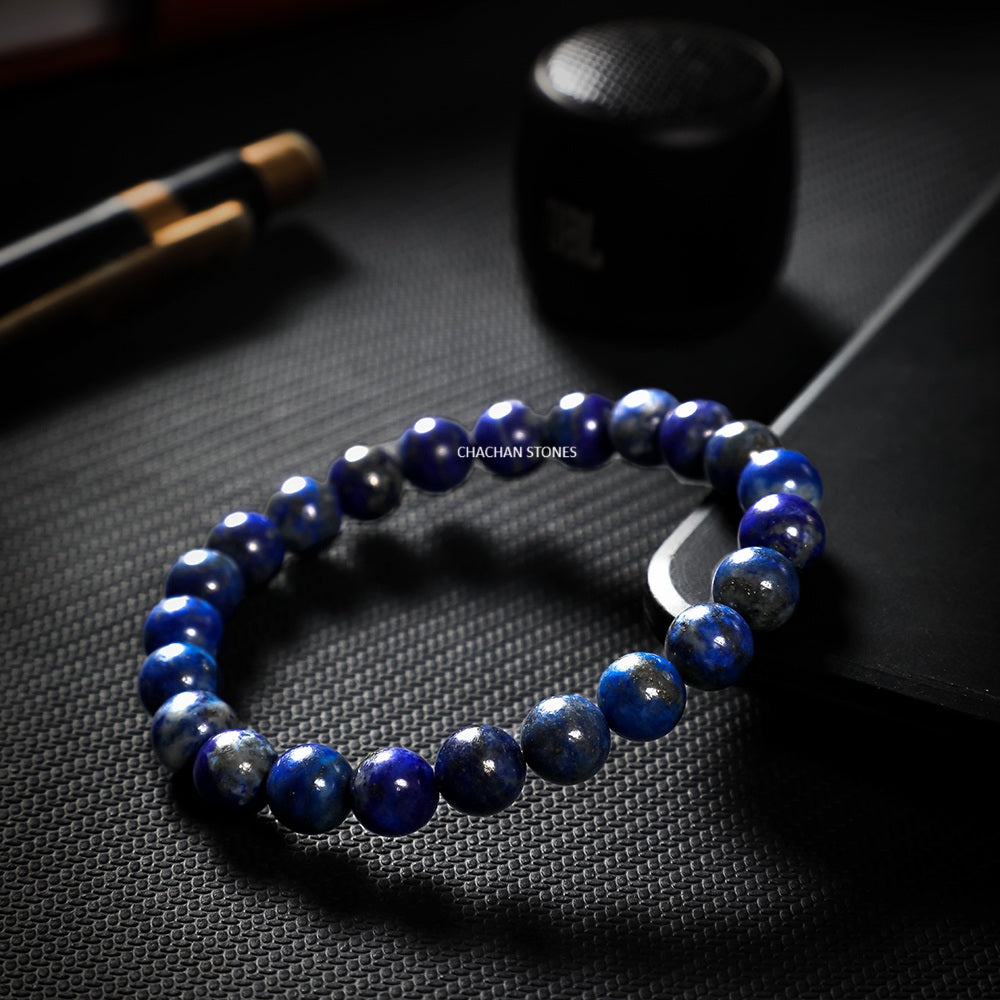 Blue beaded bracelet on a dark textured surface with 'CHACHAN STONES' branding.