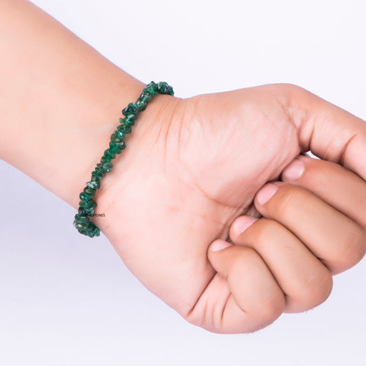Hand wearing a green beaded bracelet on a light background