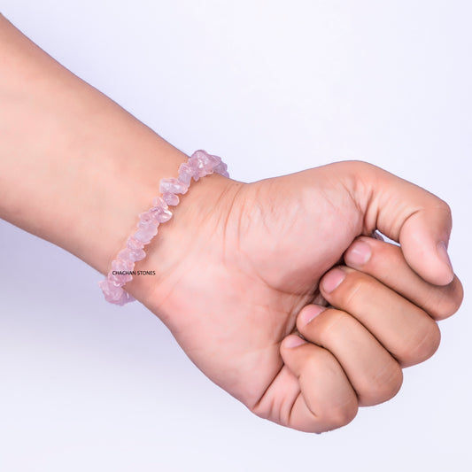 Hand wearing a pink beaded bracelet on a light purple background